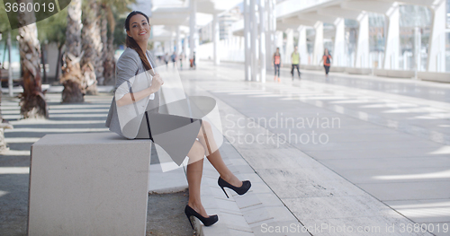 Image of Elegant woman sitting on a bench on a promenade