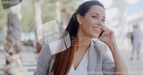 Image of Woman leaning on a wall chatting on a mobile