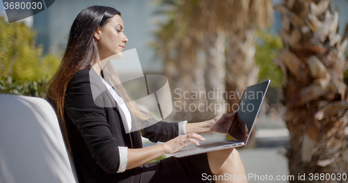 Image of Businesswoman sitting working in an urban park