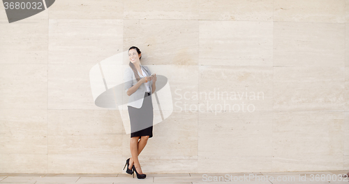 Image of Stylish businesswoman standing against a wall