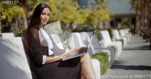 Image of Young woman working on a laptop in the park