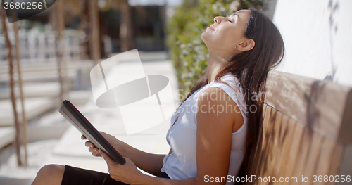Image of Young businesswoman relaxing on an outdoor bench