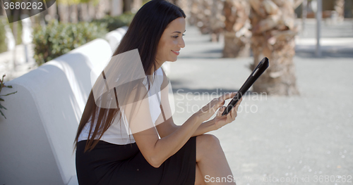 Image of Smiling young woman using her tablet outdoors
