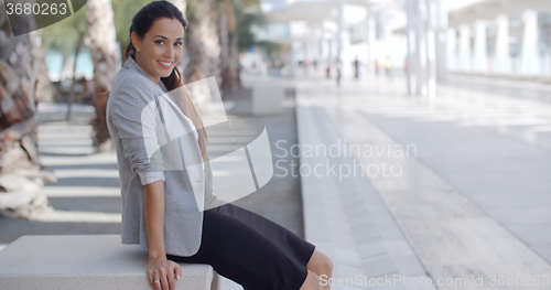 Image of Elegant woman sitting on a bench on a promenade