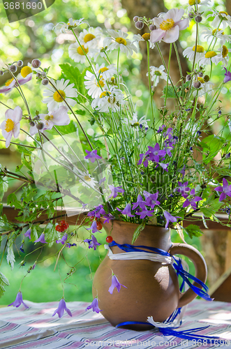 Image of Jug with a bouquet of summer flowers on a table in the garden