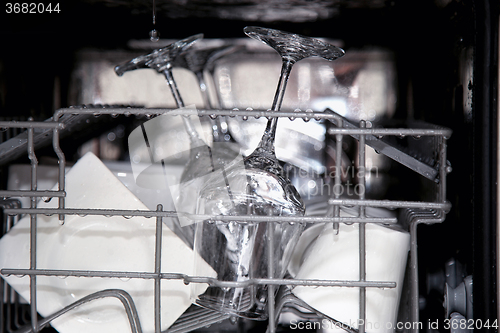 Image of details of open dishwasher, utensils with drops in during washin