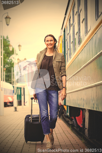 Image of woman traveler with luggage walking on the platform