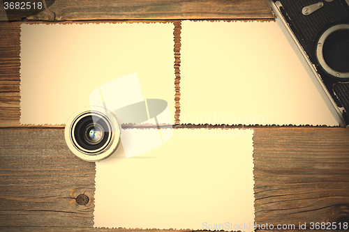 Image of mock up photo, lens and vintage camera on wooden table