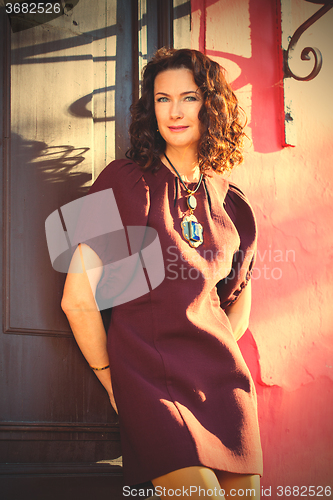 Image of woman in burgundy dress near ancient door