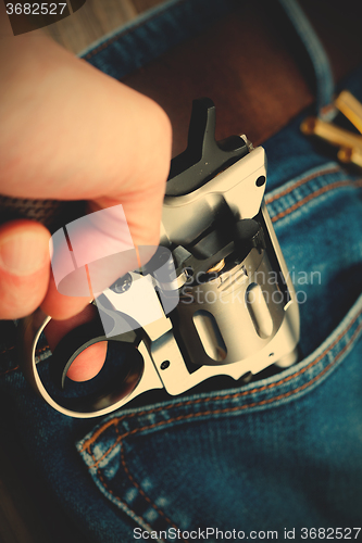 Image of hand pulls out a revolver from the pocket