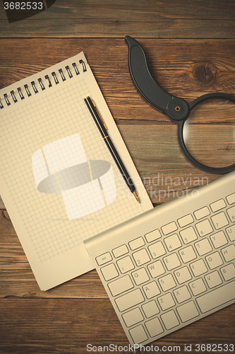 Image of notebook, pen, magnifying glass and computer keyboard
