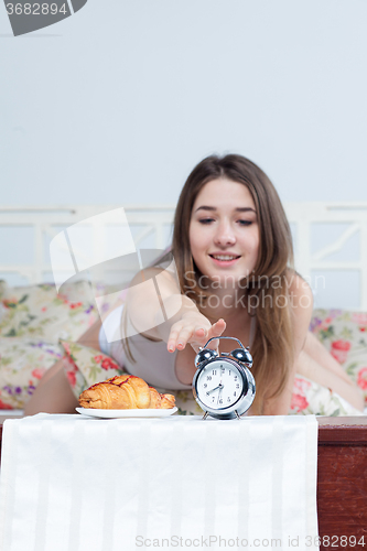 Image of The young girl in bed with  clock service