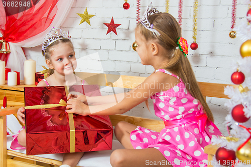 Image of The girl gave a big red Christmas gift to his sister