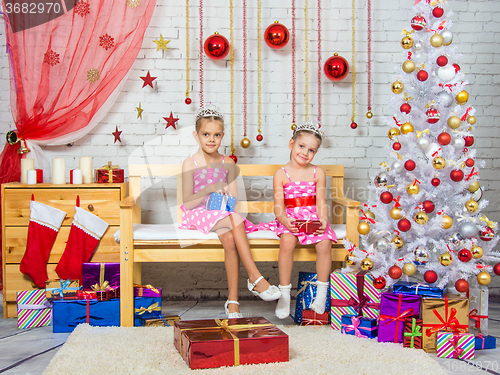 Image of Happy sister holding gifts in their hands, and sit on a bench in a Christmas setting