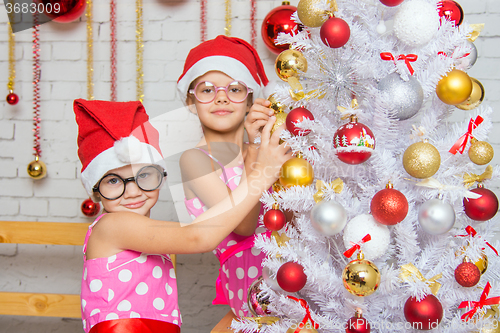 Image of Two funny girls hanging balls on the Christmas tree