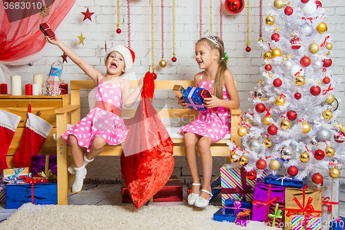 Image of Two girls having fun and happy New Year gifts from Santa Claus bag