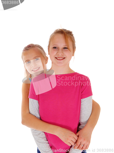 Image of Smiling sisters standing behind each other.