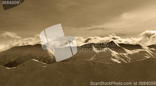 Image of Sepia winter mountains at evening and sunlight clouds