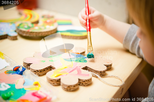 Image of Little female baby painting with colorful paints