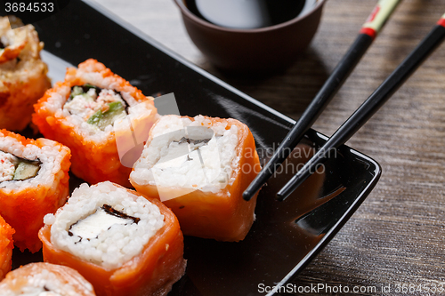 Image of Sushi roll with chopsticks