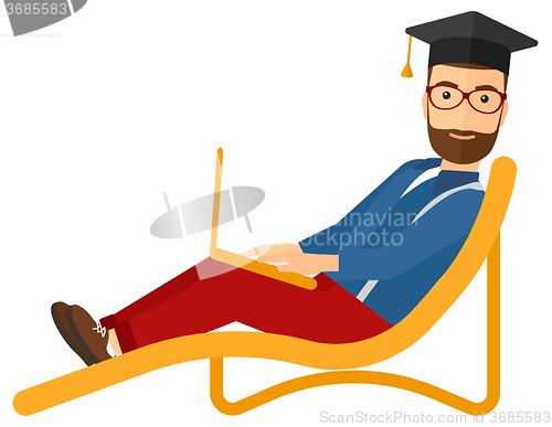 Image of Graduate lying on chaise lounge with laptop.