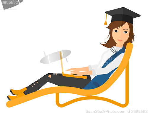 Image of Graduate lying in chaise lounge with laptop.