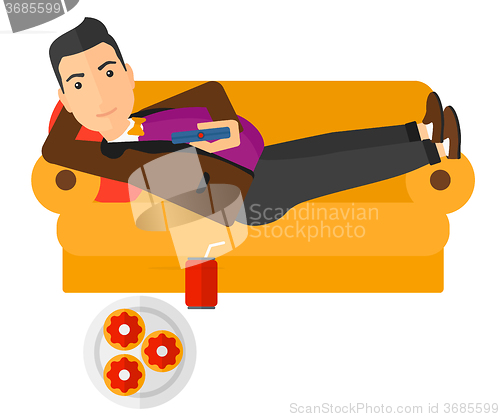 Image of Man lying on sofa with junk food.