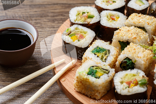 Image of Sushi rolls with salmon and hot tea ceremony on black wooden table