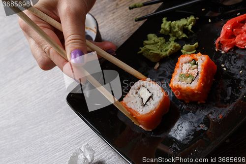 Image of Sushi. Hand with chopsticks