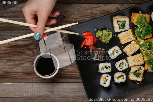 Image of Sushi. Hand with chopsticks