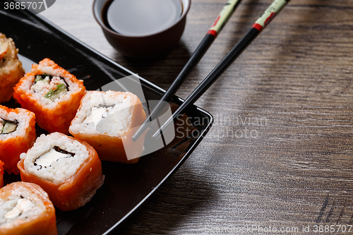 Image of Sushi roll with chopsticks