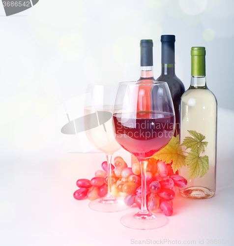 Image of wineglass, bottles of wine and grapes