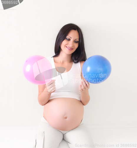 Image of pregnant woman with blue and pink balloon