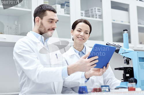 Image of scientists with tablet pc and microscope in lab