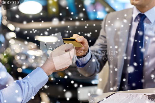 Image of customer giving credit card to car dealer in salon