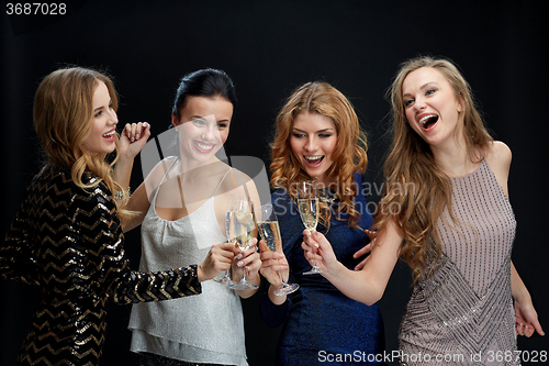 Image of happy women clinking champagne glasses over black