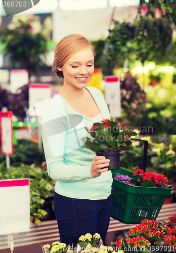 Image of happy woman with shopping basket choosing flowers