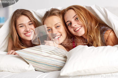 Image of happy young women in bed at home pajama party