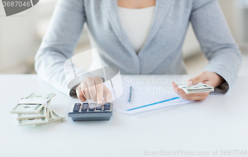 Image of close up of hands counting money with calculator