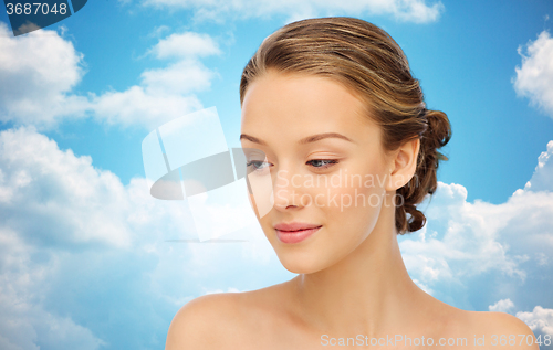 Image of smiling young woman face over blue sky