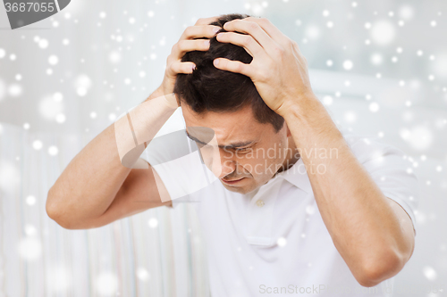 Image of unhappy man suffering from head ache at home