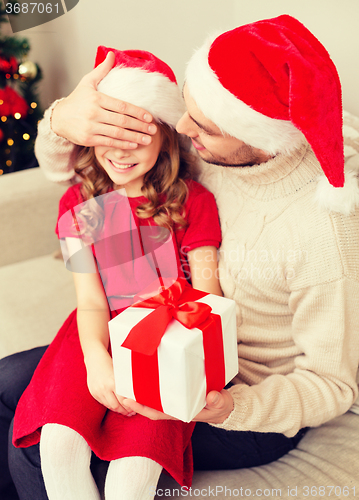 Image of smiling father surprises daughter with gift box