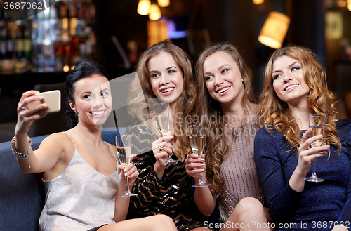 Image of women with champagne taking selfie at night club