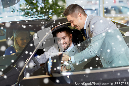 Image of happy couple with car dealer in auto show or salon