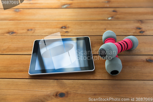 Image of close up of dumbbells and tablet pc on wood