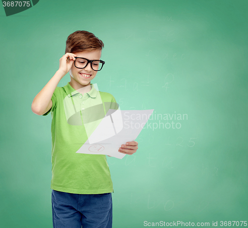 Image of happy boy in eyeglasses holding school test result