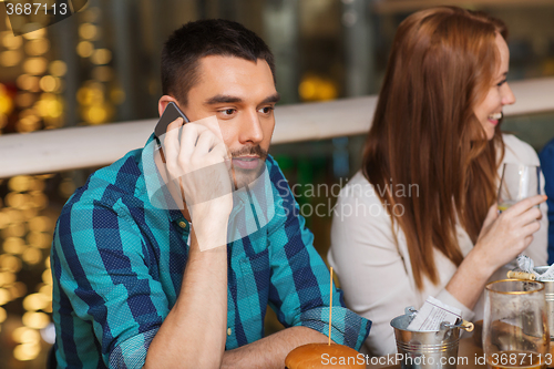 Image of man with smartphone and friends at restaurant