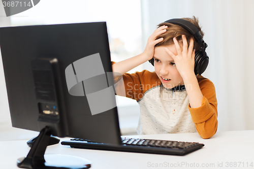 Image of terrified boy with computer and headphones at home