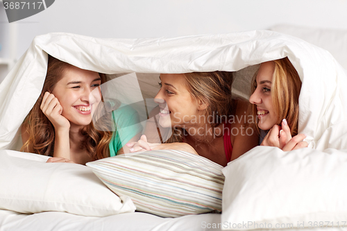 Image of happy young women in bed at home pajama party