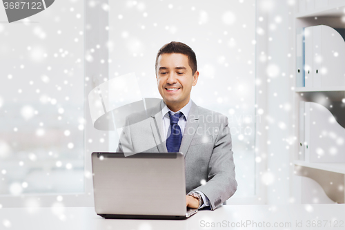 Image of happy businessman working with laptop in office